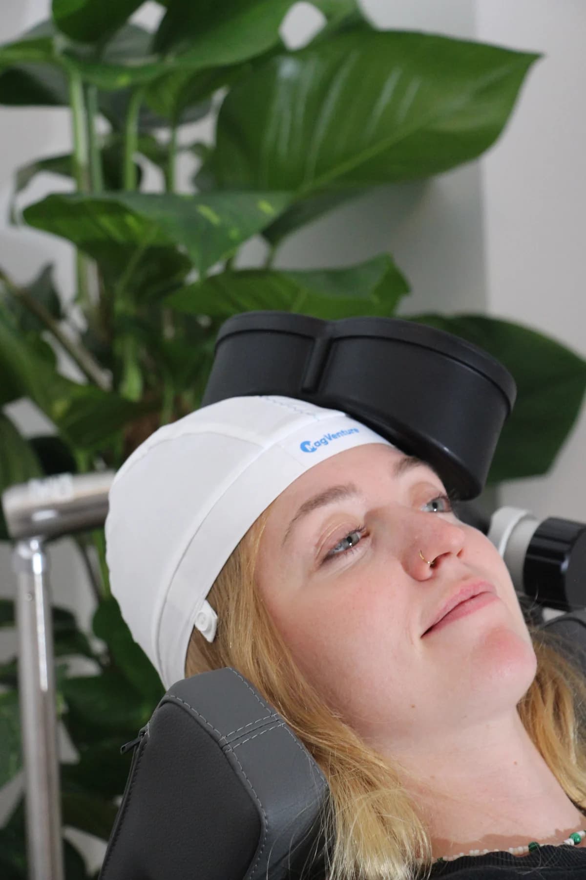 Die Magnetspule liegt am Kopf einer Patientin an, die wach im Behandlungsstuhl sitzt